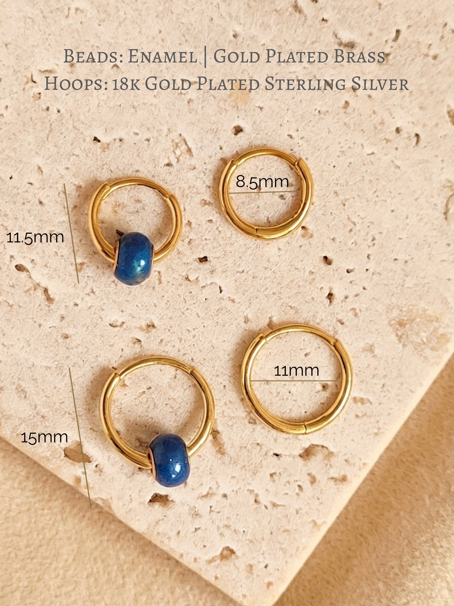 Set of mini blue enamel bead huggie hoop earrings on an aesthetic beige stone surface with dimensions