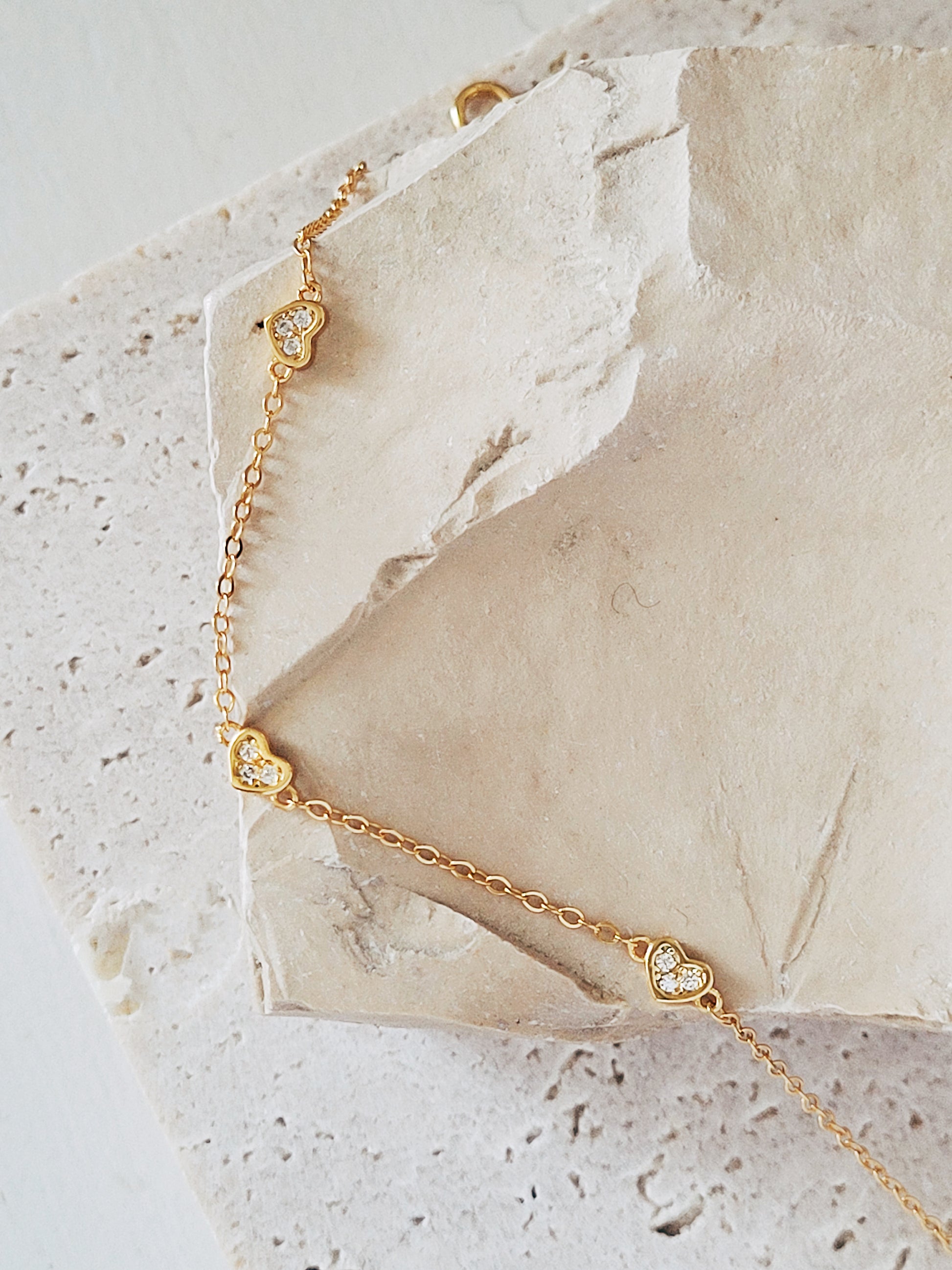 The mini heart bracelet is placed on a rock to showcase its detailed craftsmanship. 