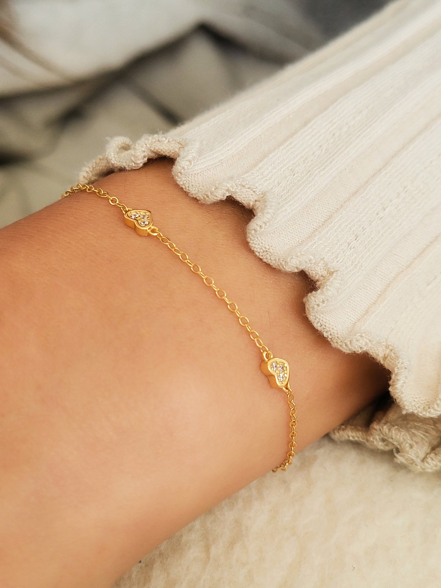 A close up on a women's waist wearing mini heart bracelet.