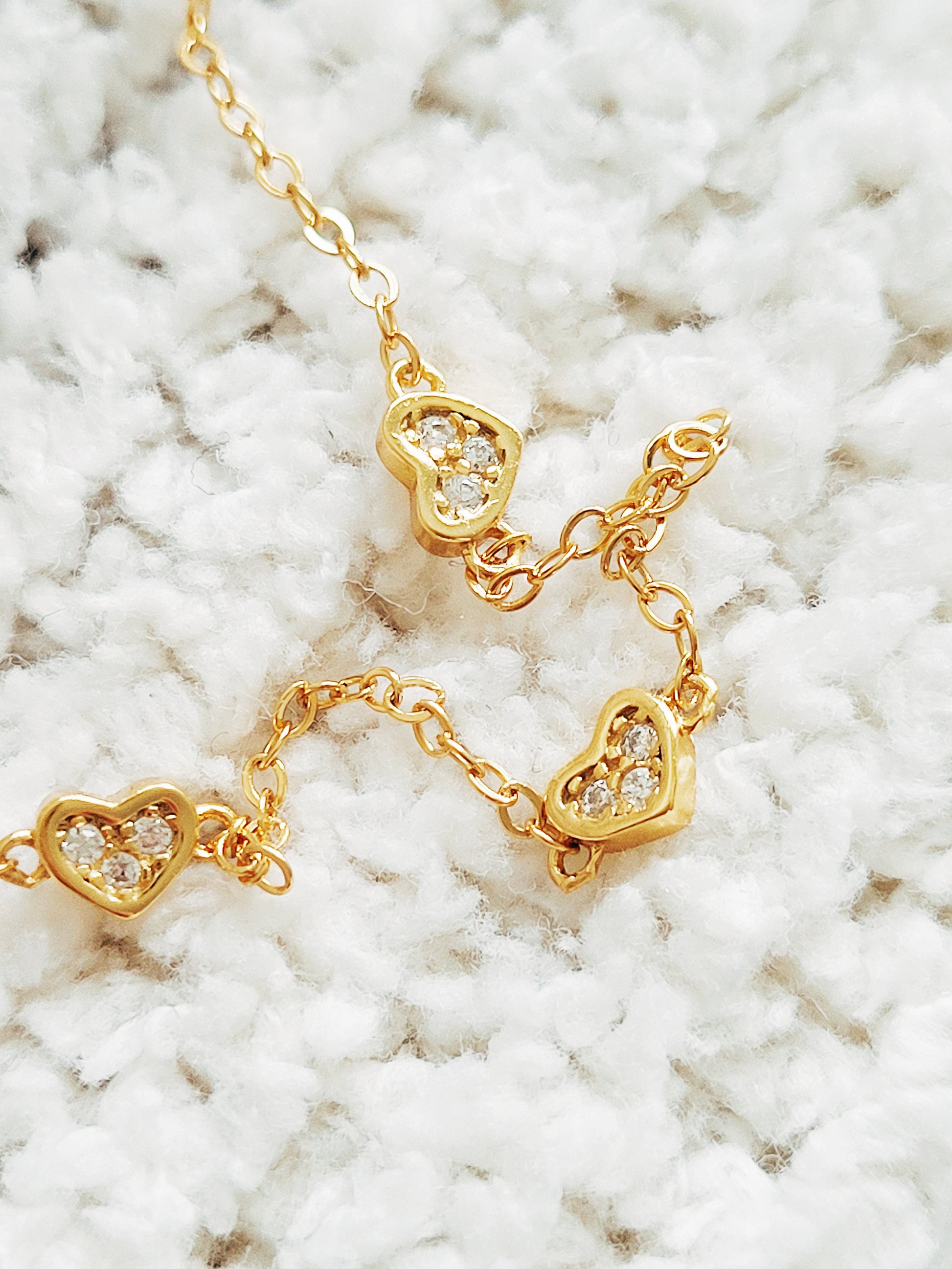 three golden heart charms on woven