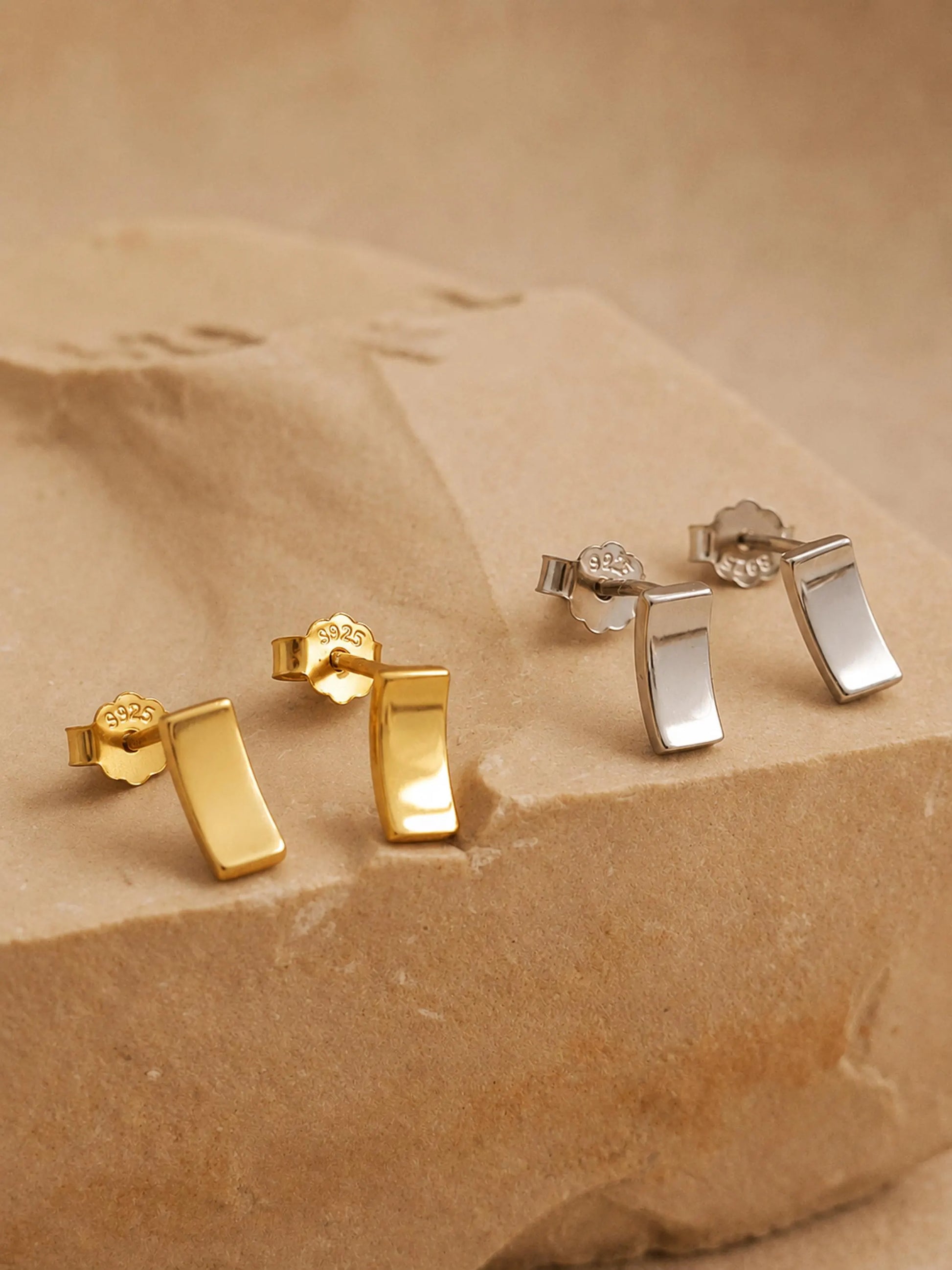 Gold and silver bar stud earrings, minimalist rectangle stud earrings in gold vermeil and sterling silver on an aesthetic beige color stone