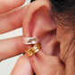 Close-up of an ear wearing a gold and silver ear cuff earring