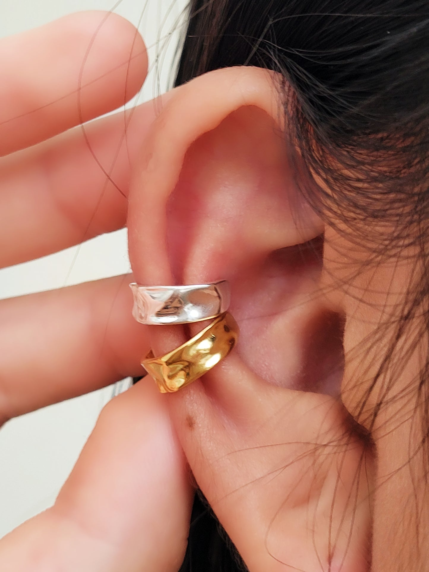Close-up of an ear wearing a gold and silver ear cuff earring