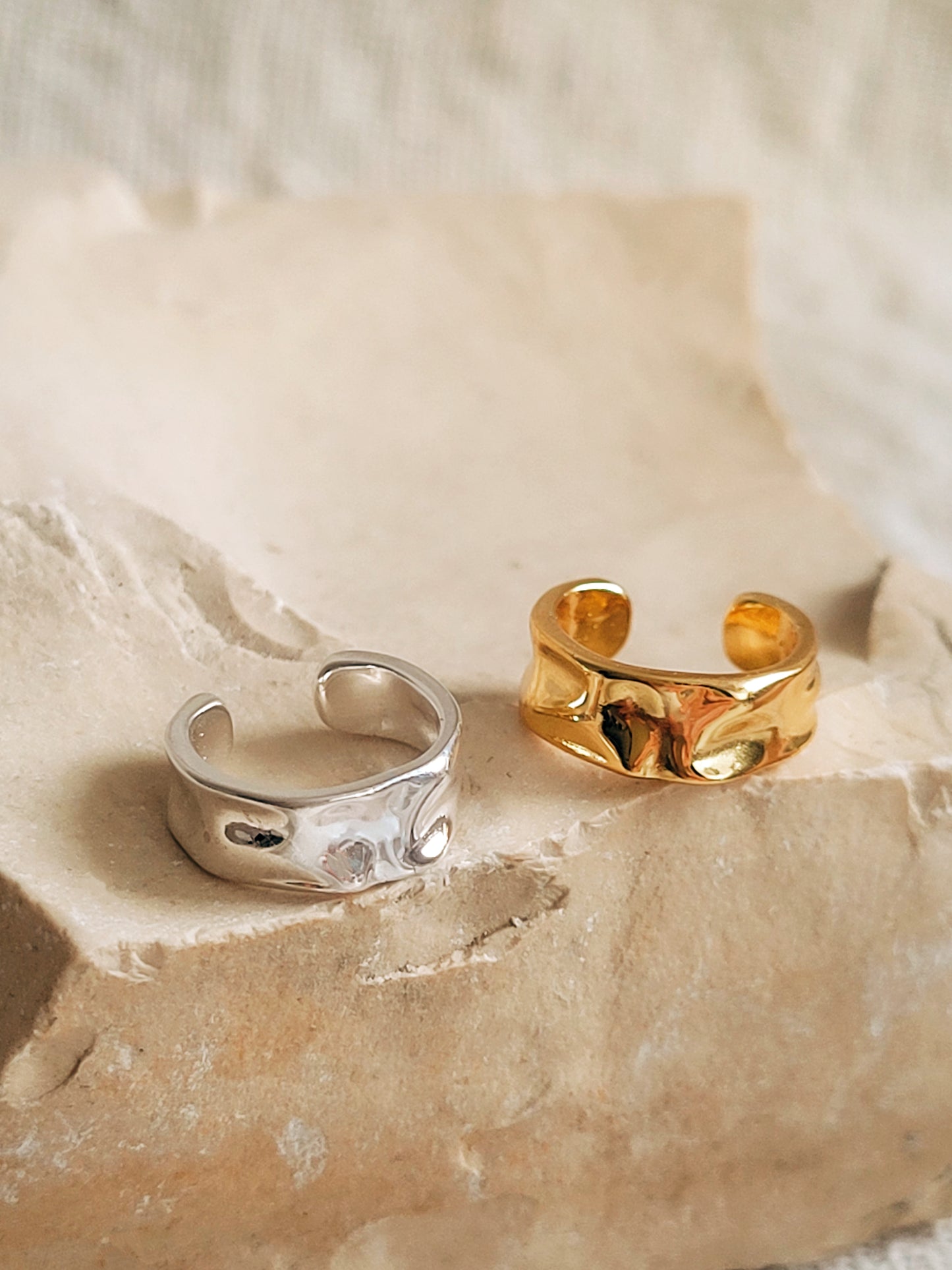 Gold and silver ear cuff earrings displayed on a rock