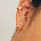 Close-up of a person wearing minimalist gold ear cuff earring against a neutral background