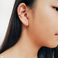 A girl wearing a textured gold ear cuff earring match with a sleek small gold hoop, dainty and minimalist style