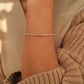 Close-up of a lady's wrist wearing a delicate mixed metal bracelet with a soft background.