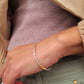 Close-up of a woman's wrist wearing a silver bangle bracelet with a beige jacket, showcasing its minimalist style