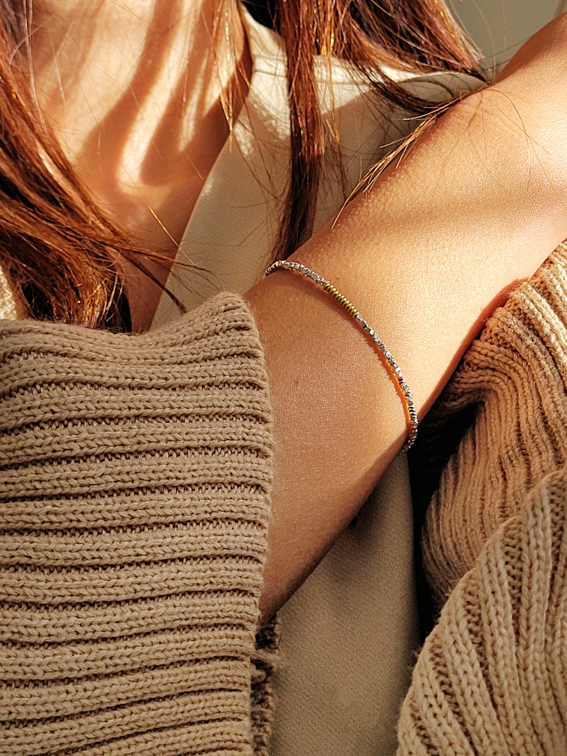 Close-up of a woman wearing a delicate bracelet with a neutral background