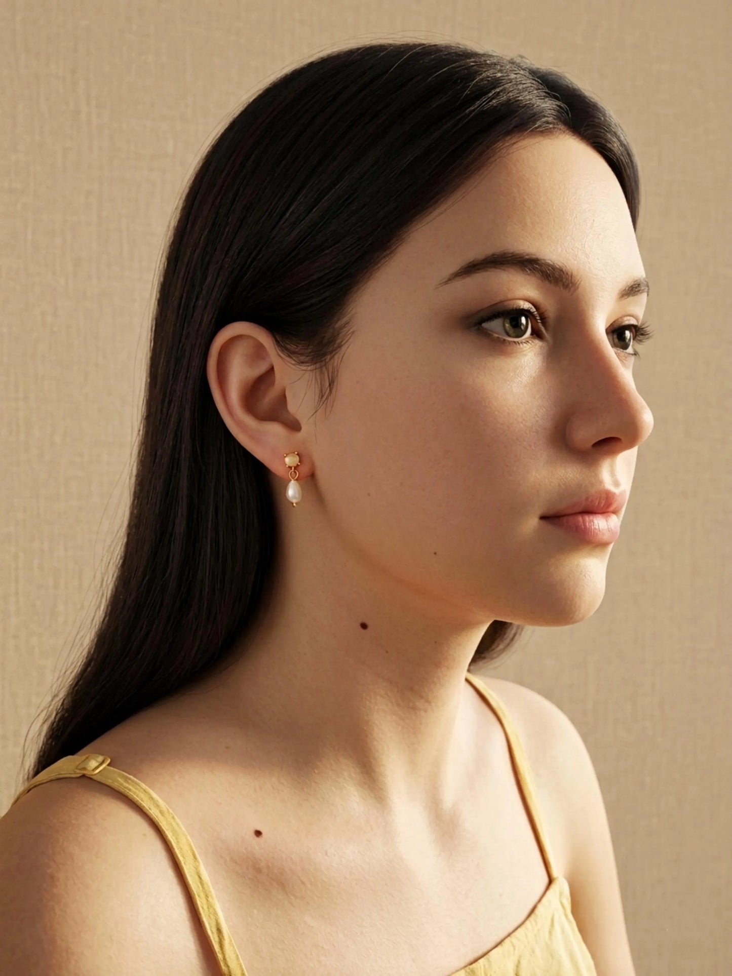 Woman with long dark hair wearing a moonstone stud earring featuring a dangly freshwater pearl drop, perfect birthday gift for june girl.