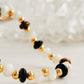 Close up of a gemstone bracelet featuring tiger's eye, mother of pearl, and black onyx beads with 22k gold vermeil accents