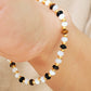 A gemstone bracelet featuring tiger's eye, mother of pearl, and black onyx beads with 22k gold vermeil accents, worn on wrist.