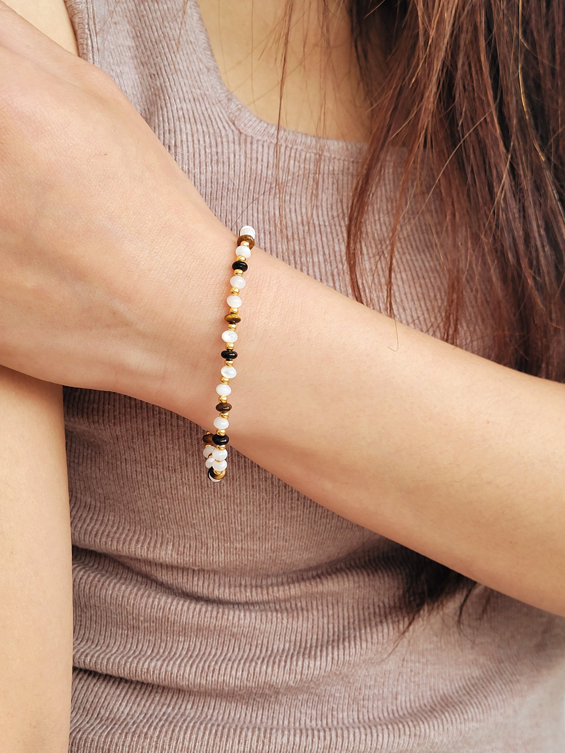 Model wearing a gemstone bracelet featuring in white, brown and gold color, showcasing its boho and luxe style