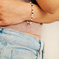 A model styled in minimalist outfit wearing a gemstone bracelet featuring tiger's eye, mother of pearl, and black onyx beads with 22k gold vermeil accents