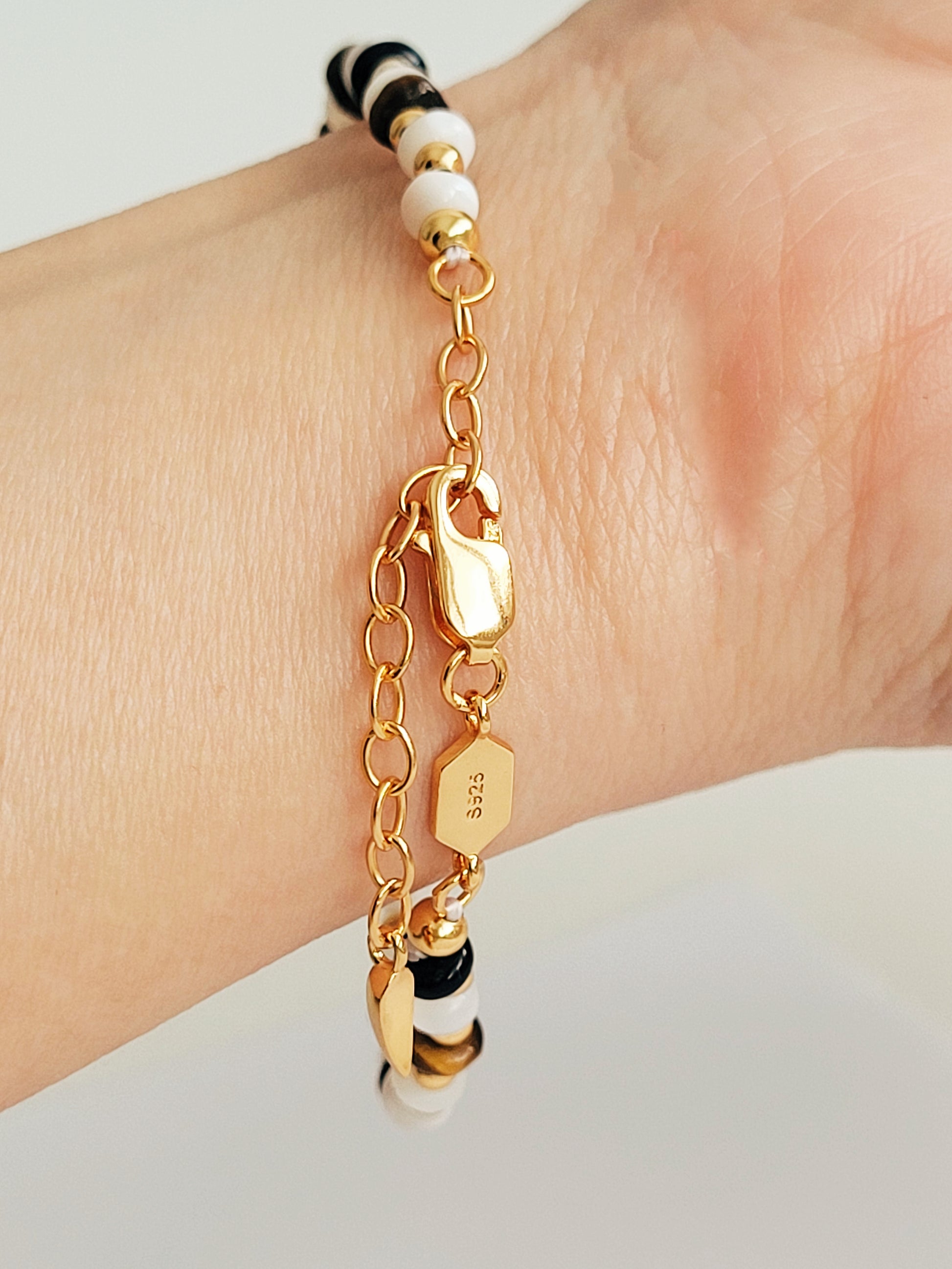 Close up of the clasp of a gemstone bracelet on a model wrist