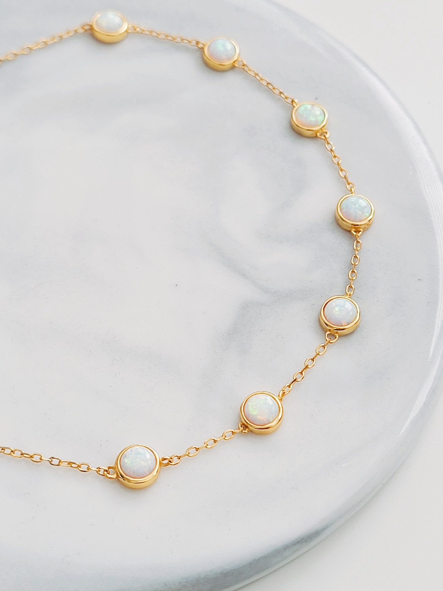 A stunning gold-plated bracelet adorned with white opal stones. Featuring 7 opal stones, perfect for layering or wear it solo.