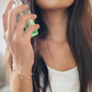 A woman elegantly holds a perfume bottle, showcasing her stunning gold-plated opal bracelet with white opal stones.