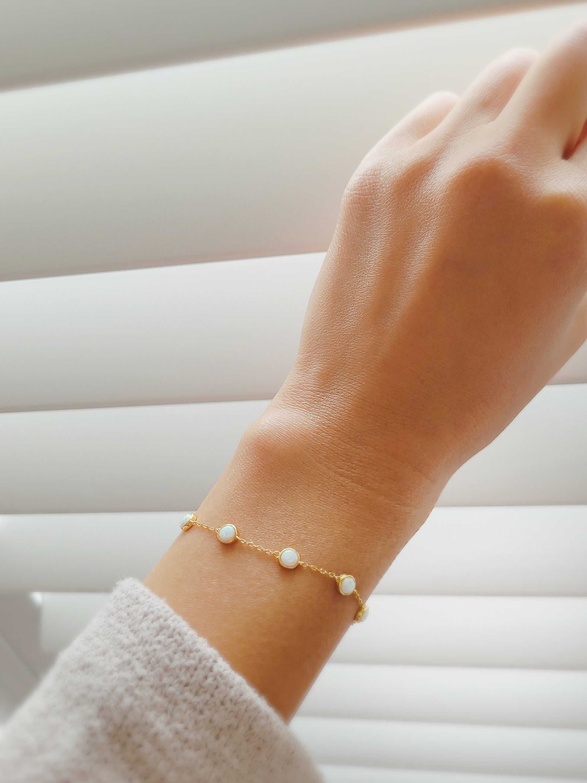 A woman hand adorned with a gold fire opal bracelet