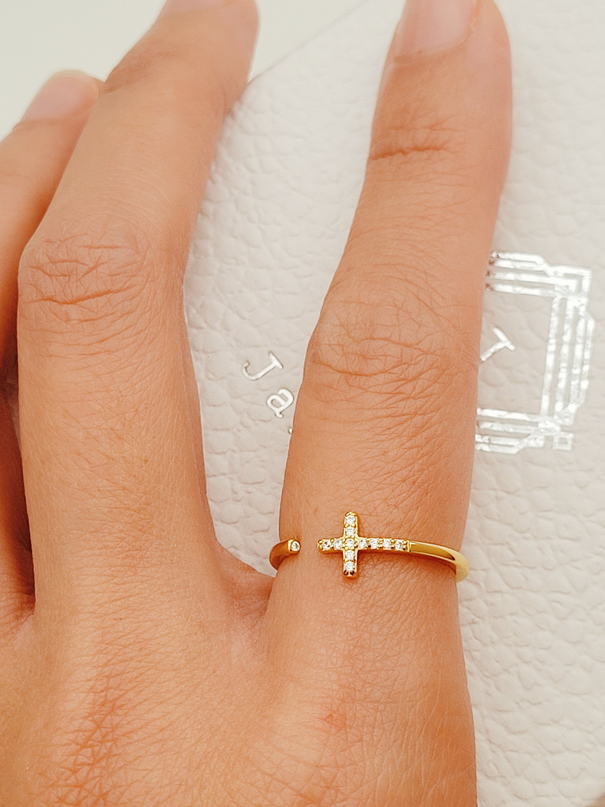 An exquisite gold ring showcasing an open cross, elegantly set with a concealed diamond for a luxurious finish.