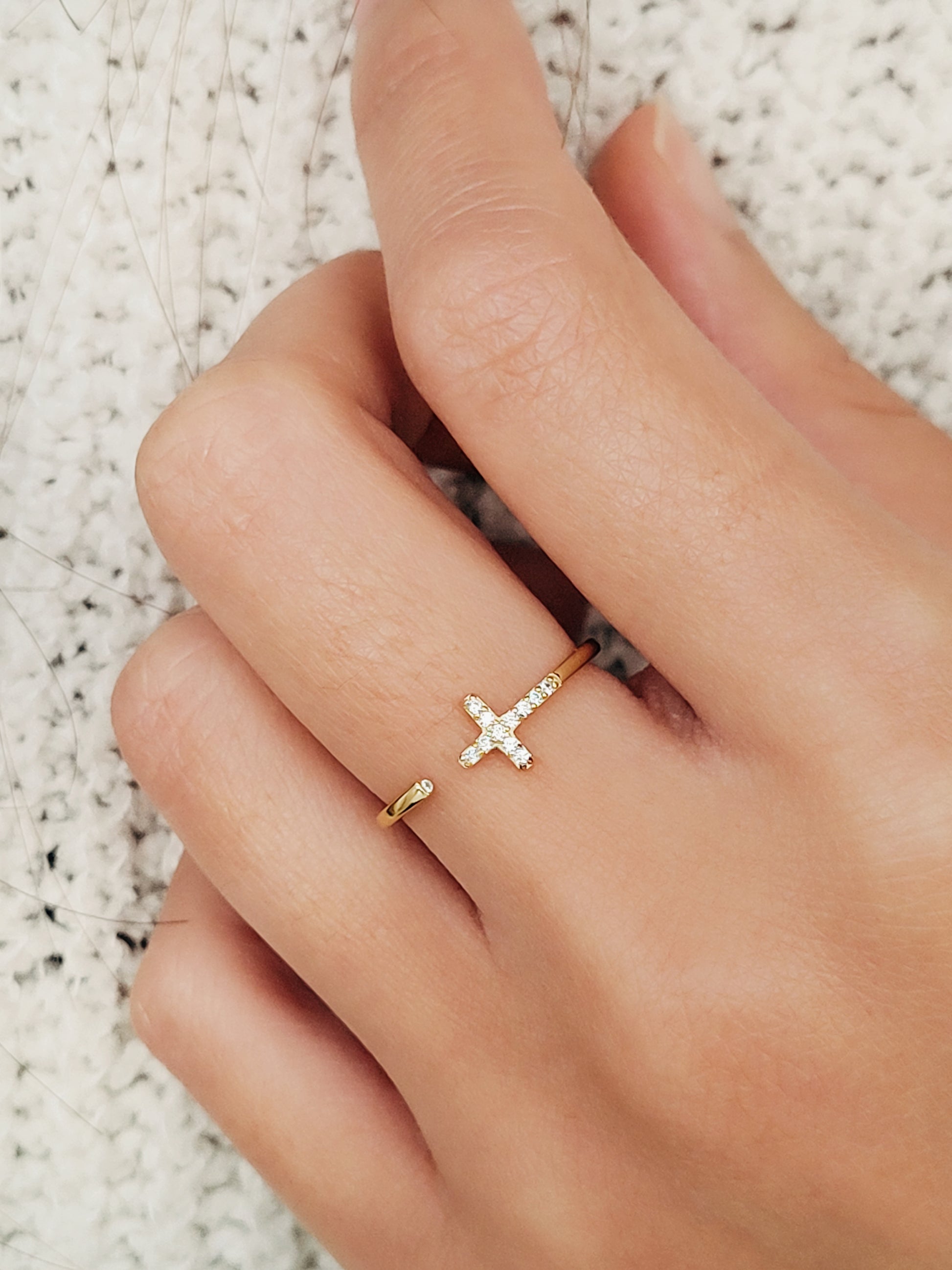 A luxurious gold cross ring featuring a pave cross and a hidden gem, exuding sophistication and charm.