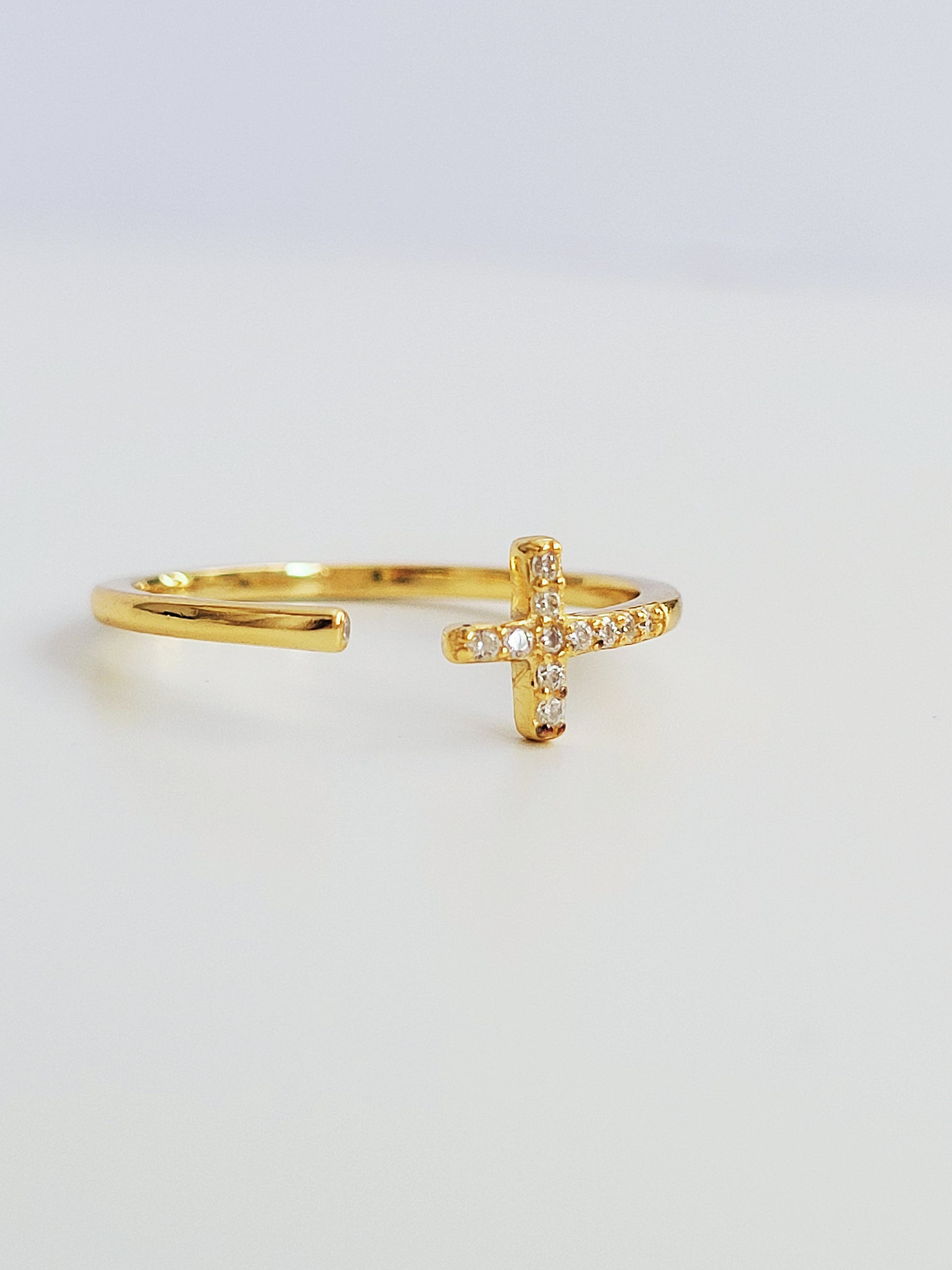 A luxurious gold cross ring featuring a pave cross and a hidden gem, exuding sophistication and charm.