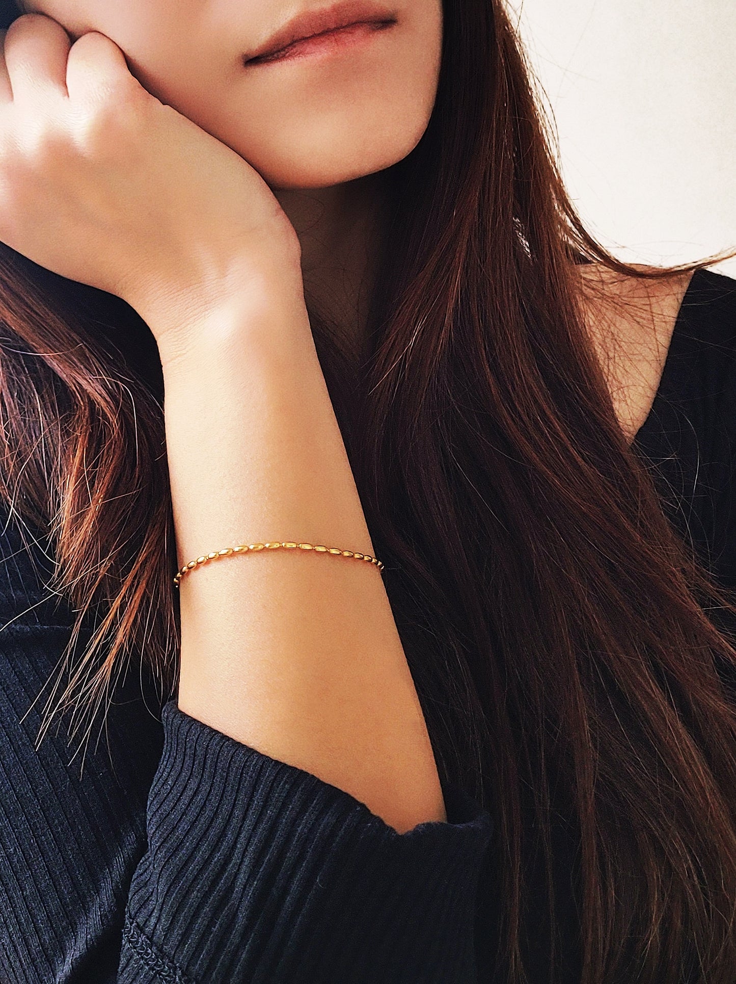 Close-up of a woman's hand wearing the elegant and dainty gold-plated oval beaded bracelet, highlighting its lustrous finish and intricate bead arrangement.