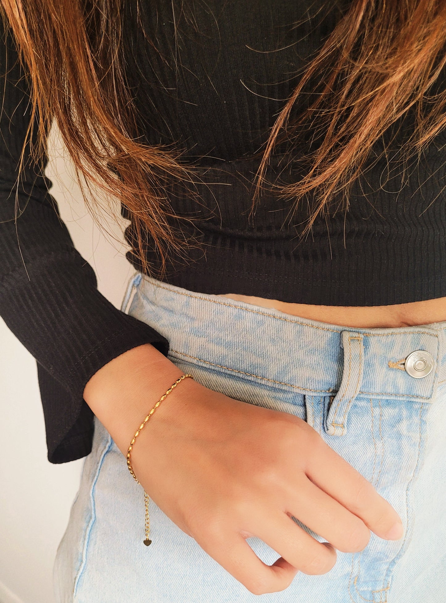 Close-up of a woman's hand wearing the elegant and dainty gold-plated oval beaded bracelet, highlighting its lustrous finish and intricate bead arrangement.