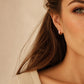 Model wearing pink enamel huggie hoop earrings in gold vermeil, dainty minimalist small gold hoop earrings.