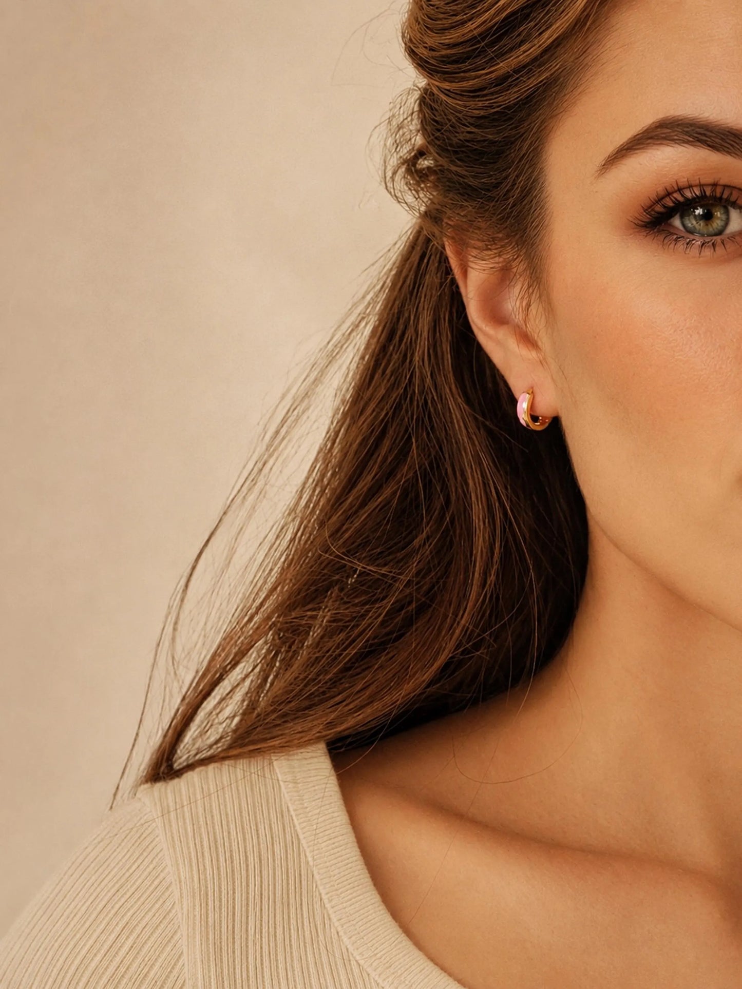 Model wearing pink enamel huggie hoop earrings in gold vermeil, dainty minimalist small gold hoop earrings.