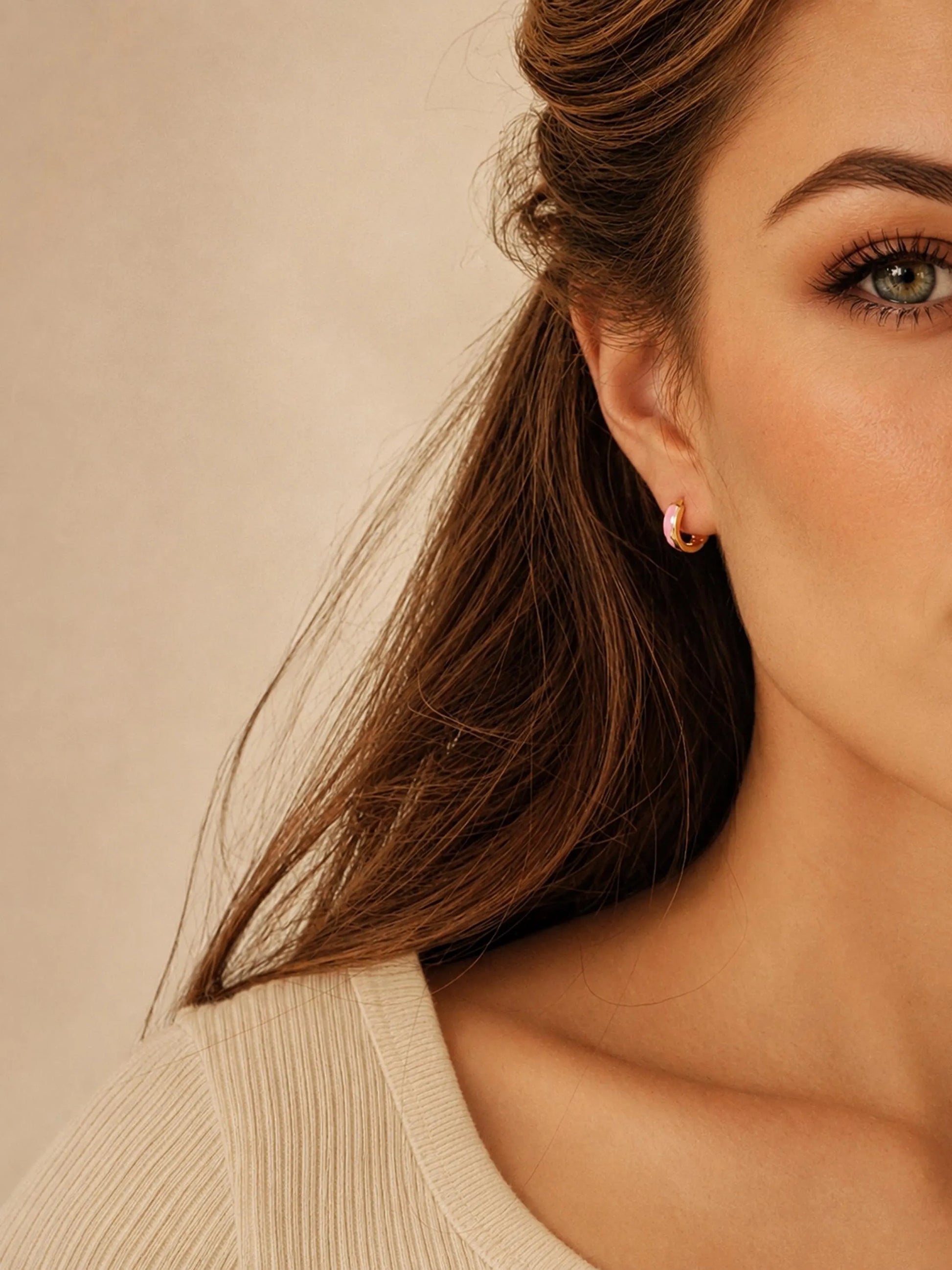 Model wearing pink enamel huggie hoop earrings in gold vermeil, dainty minimalist small gold hoop earrings.