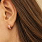 Side view of model wearing pink enamel huggie earrings in gold vermeil, dainty minimalist small gold hoop earrings.