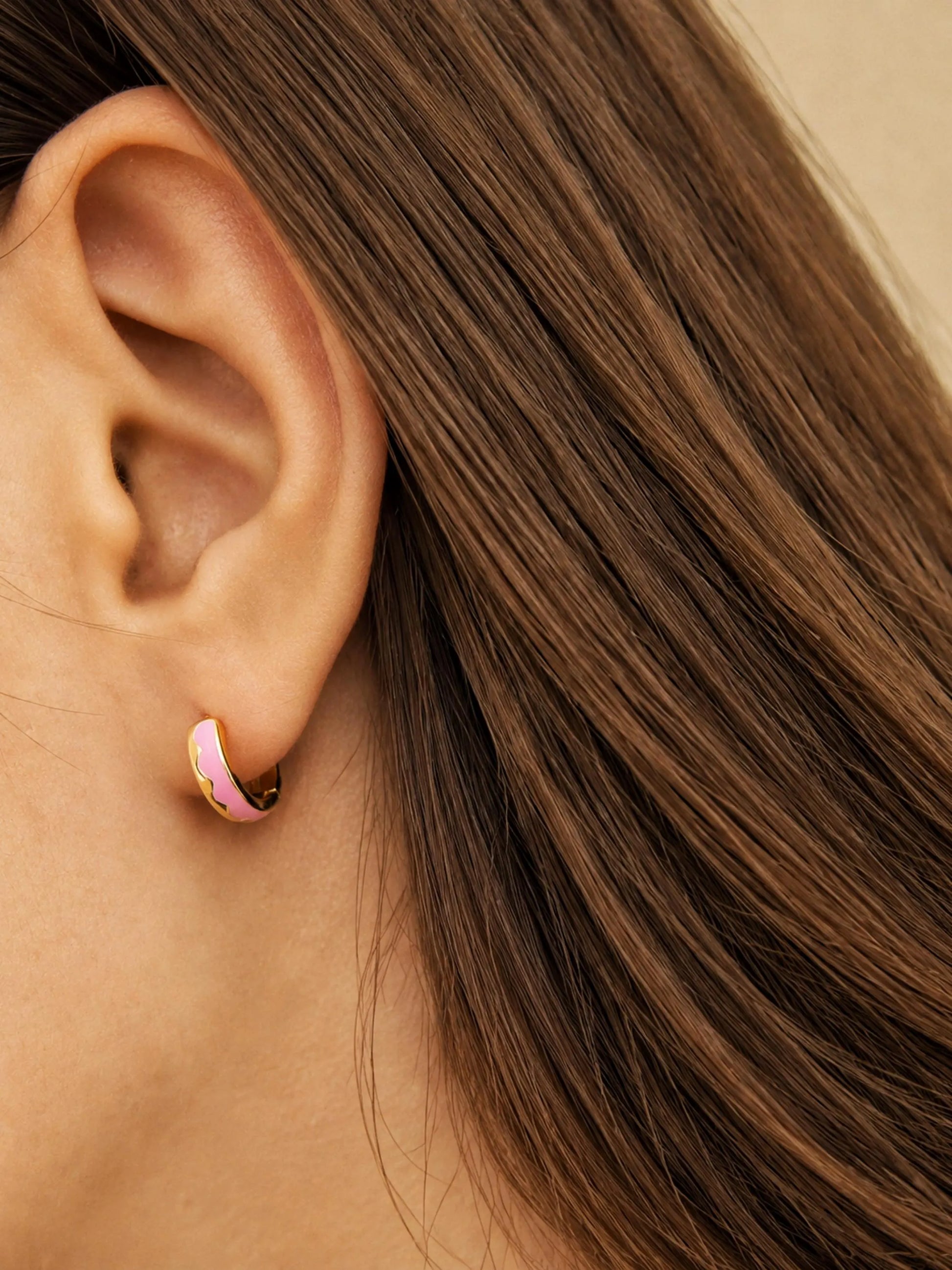 Side view of model wearing pink enamel huggie earrings in gold vermeil, dainty minimalist small gold hoop earrings.