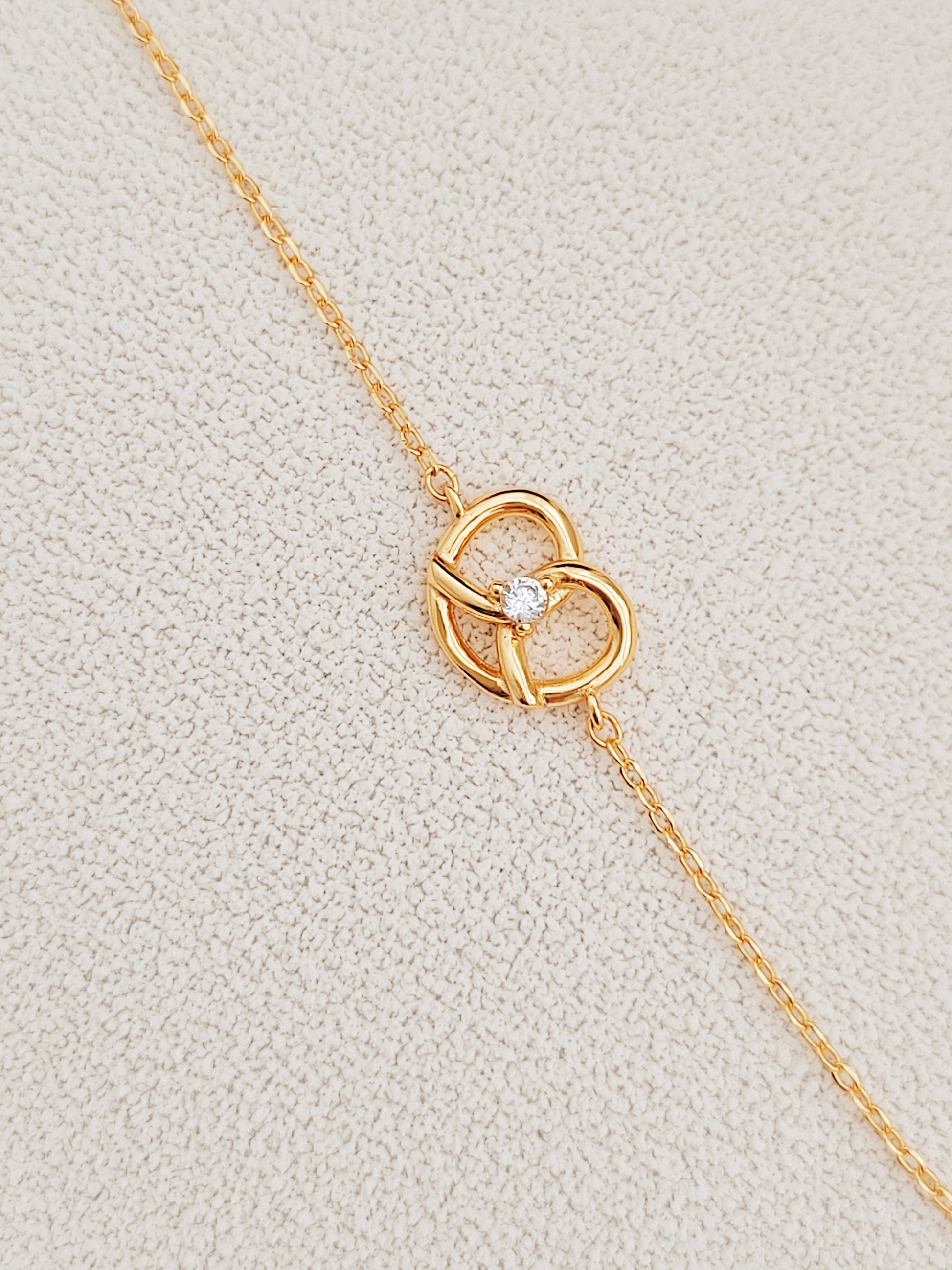 Exquisite 18ct gold-plated sweet pretzel bracelet adorned with a sparkling diamond, embodying elegance and luxury.