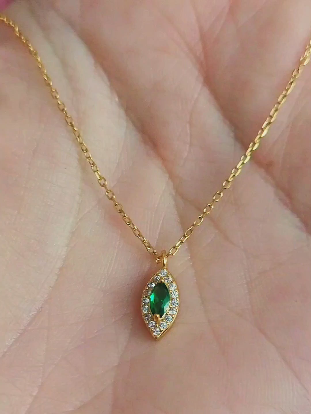 Close-up of a marquise emerald green evil eye pendant necklace on a delicate gold chain, showcasing its dainty and elegant vintage-inspired design.