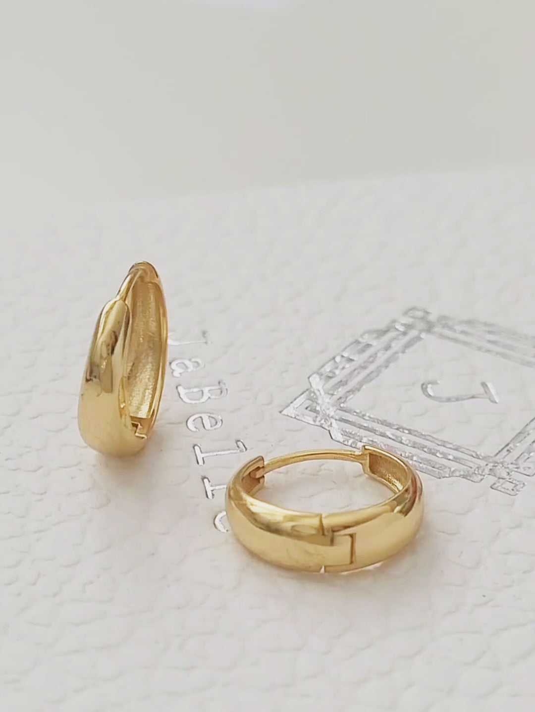 displaying a pair of dome shaped tapered gold hoop earrings