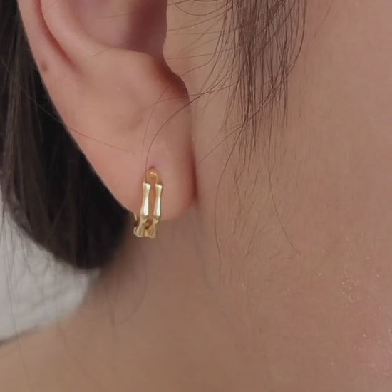 Close-up image of double hoop huggie earrings in octagon shape, featuring a minimalist gold geometric design, worn on an ear. Perfect for everyday wear.