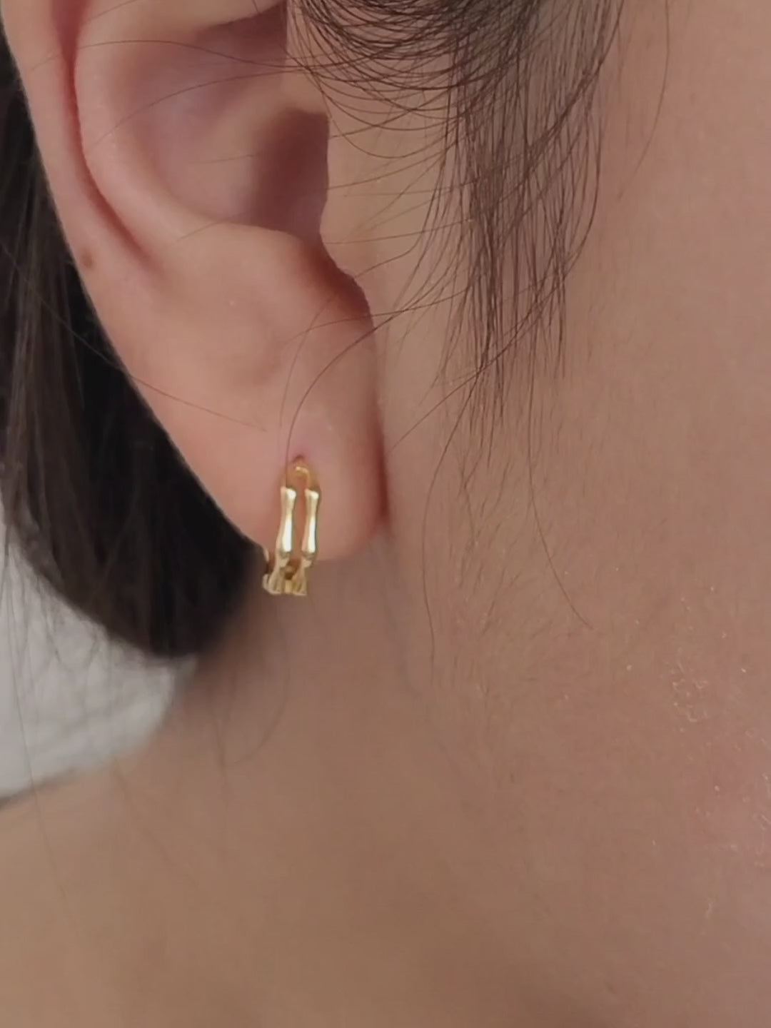 Close-up image of double hoop huggie earrings in octagon shape, featuring a minimalist gold geometric design, worn on an ear. Perfect for everyday wear.