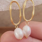 Woman wearing gold hoop earrings with freshwater baroque pearl drop for wedding.