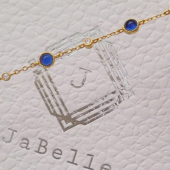 A luxurious 18ct gold plated over sterling silver chain adorned with exquisite blue sapphires and sparkling zircons, showcasing a stunning sapphire station bracelet design.