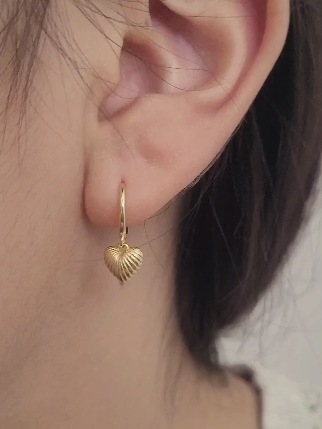 Close-up of gold plated sterling silver heart dangle earrings. Simple, classic and minimalist design perfect for everyday wear.