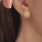 Close-up of a woman wearing a small, vintage-inspired gold stud earring with a floral ceramic tile design in pink, green, and red, styled in Victorian Gothic fashion. The earring sits elegantly on her earlobe, adding a touch of classic sophistication.