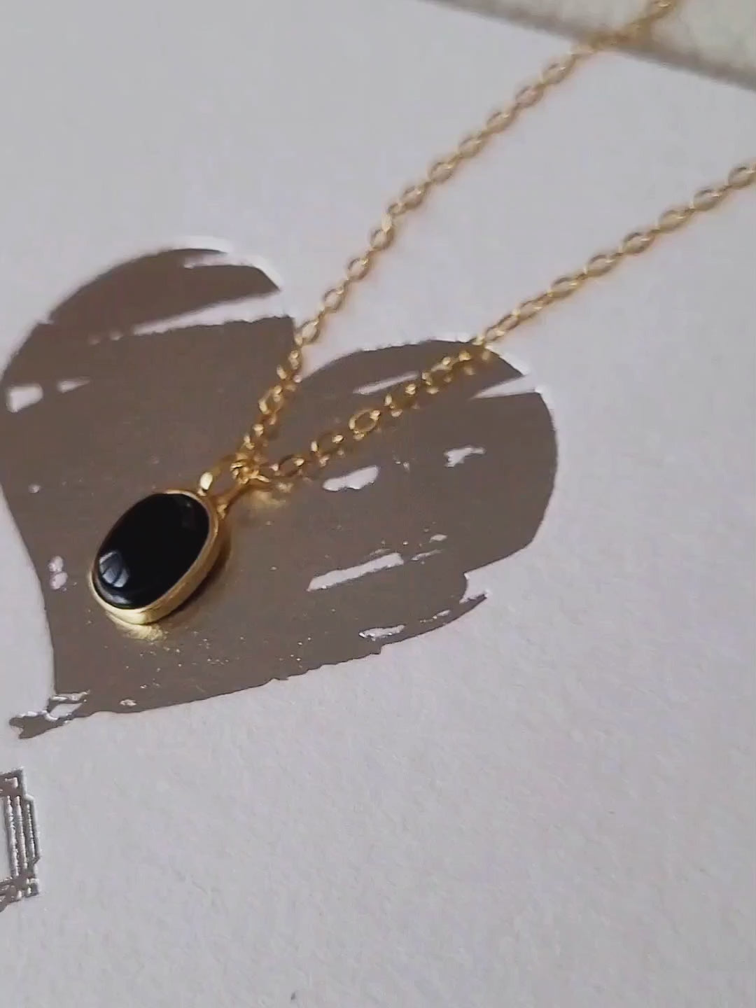 Minimalist black onyx pendant necklace with a gold-plated frame on a delicate chain.