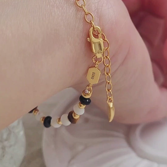 Handcrafted gemstone bracelet featuring tiger's eye, mother of pearl, and black onyx beads with 22k gold vermeil accents, worn on wrist.