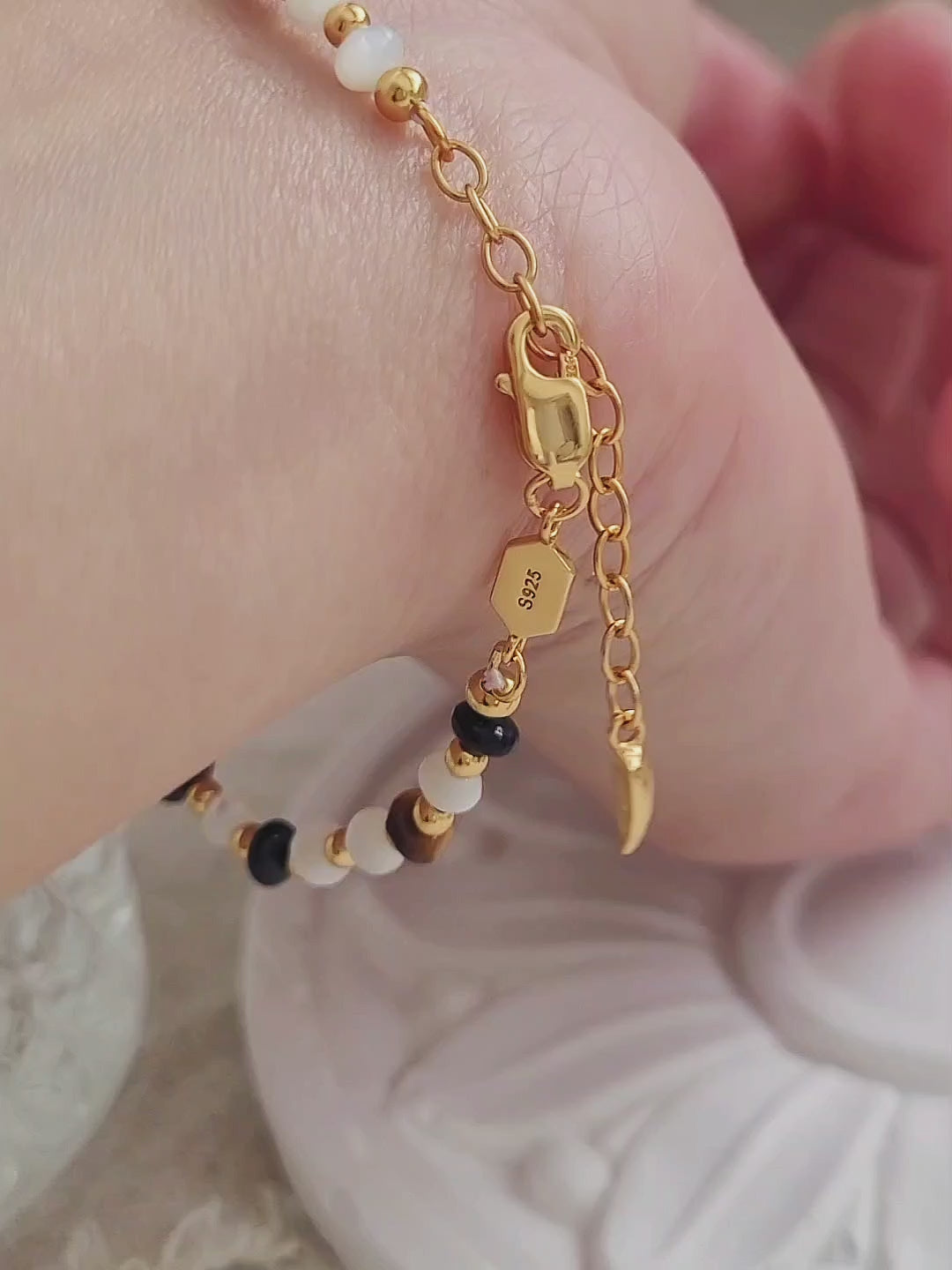 Handcrafted gemstone bracelet featuring tiger's eye, mother of pearl, and black onyx beads with 22k gold vermeil accents, worn on wrist.