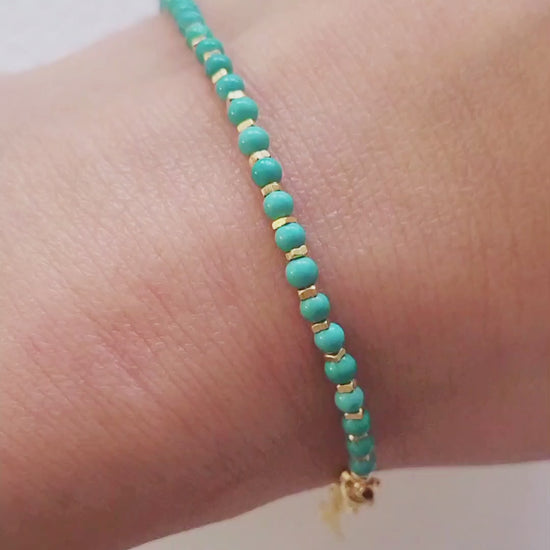 Close up of a woman's wrist wearing a Gold Turquoise beaded bracelet. Crafted in high quality natural turquoise gemstone intersecting with gold vermeil beads.