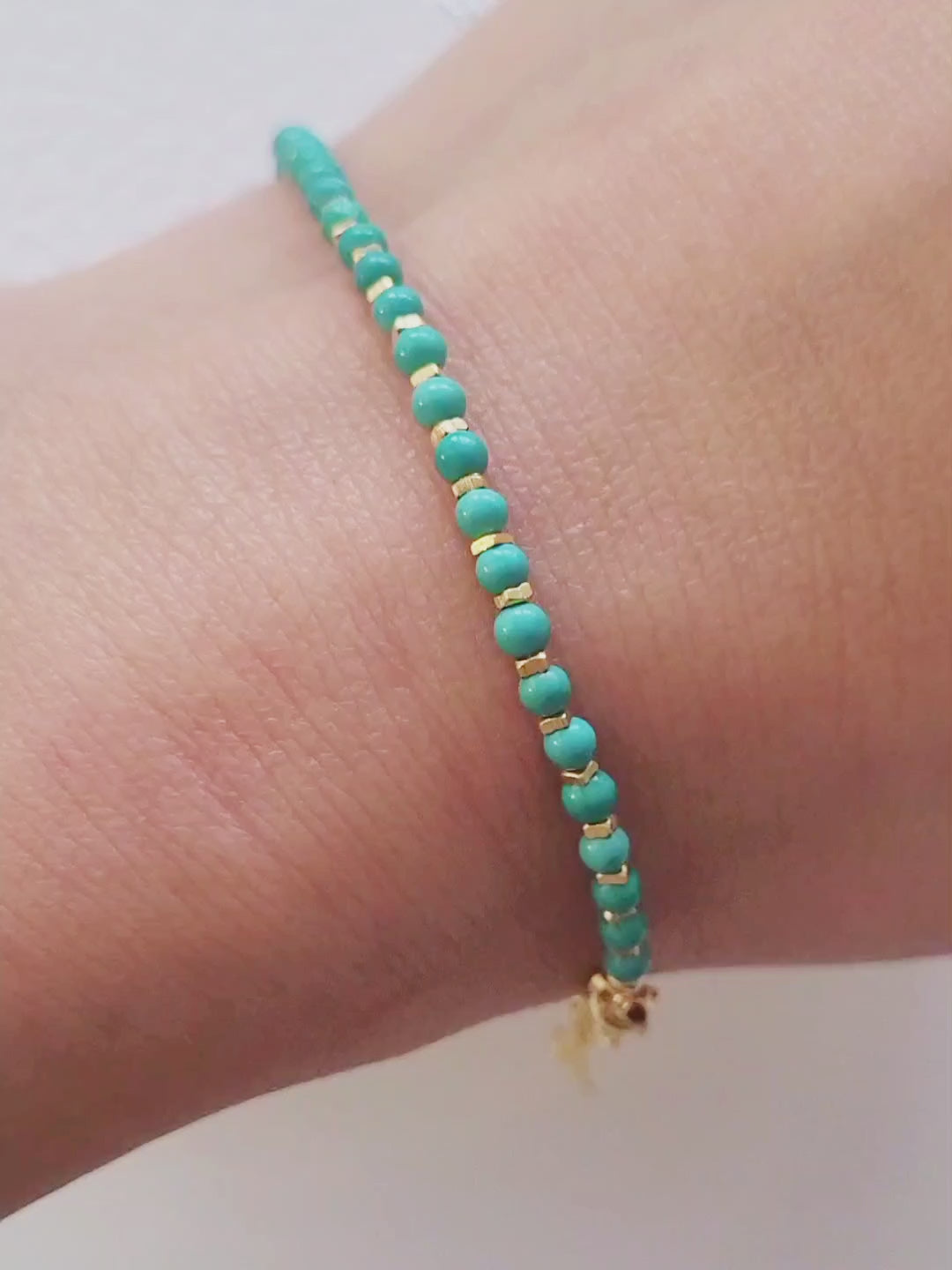 Close up of a woman's wrist wearing a Gold Turquoise beaded bracelet. Crafted in high quality natural turquoise gemstone intersecting with gold vermeil beads.