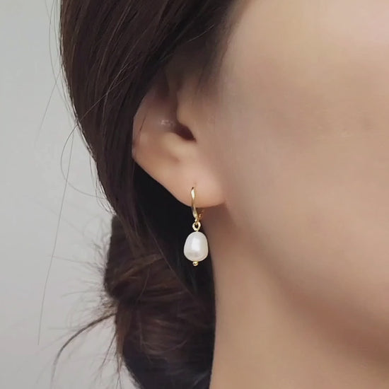 Close-up of a woman wearing a gold-plated pearl drop earring, showcasing its elegant and minimalist design.