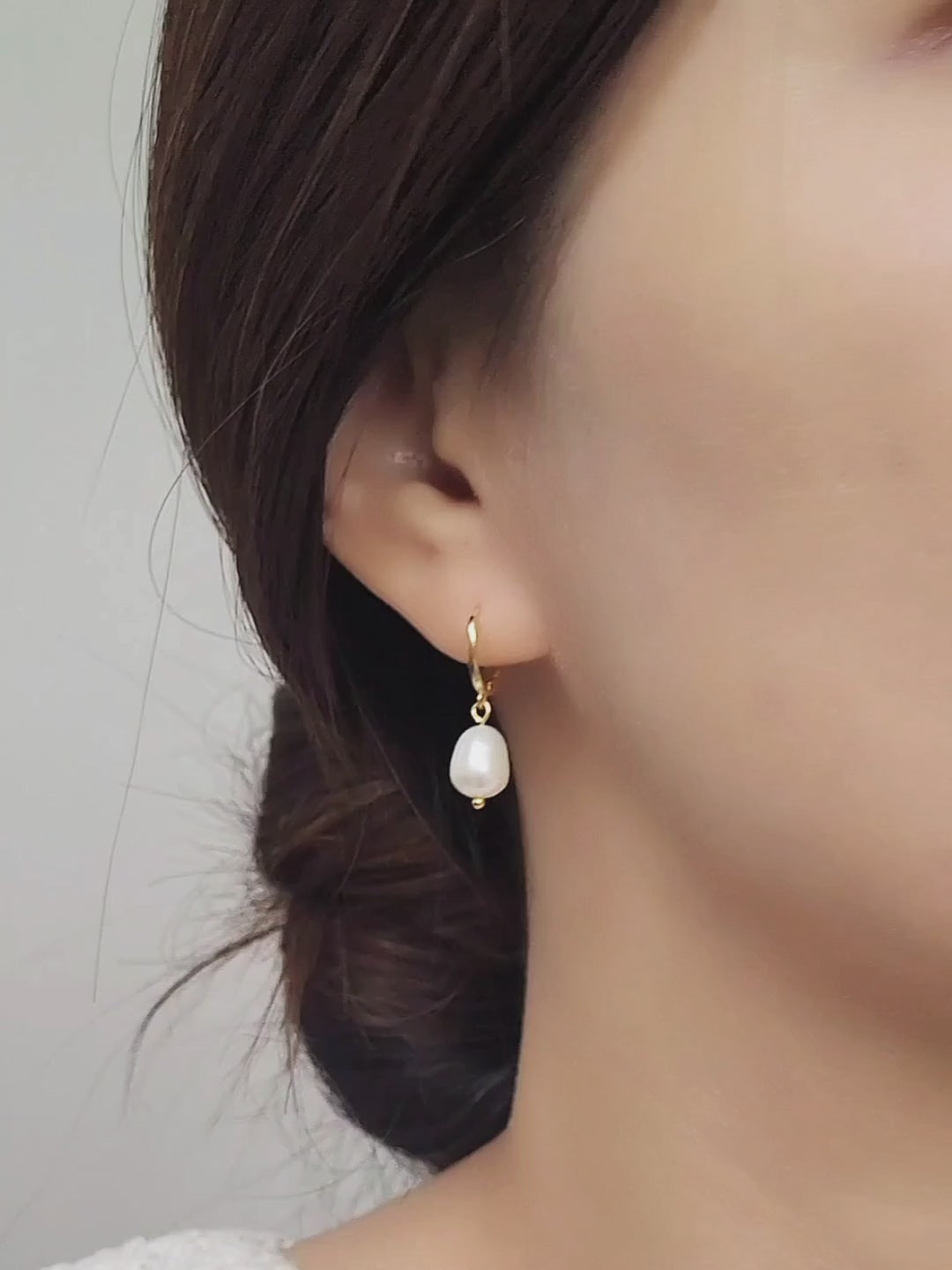 Close-up of a woman wearing a gold-plated pearl drop earring, showcasing its elegant and minimalist design.