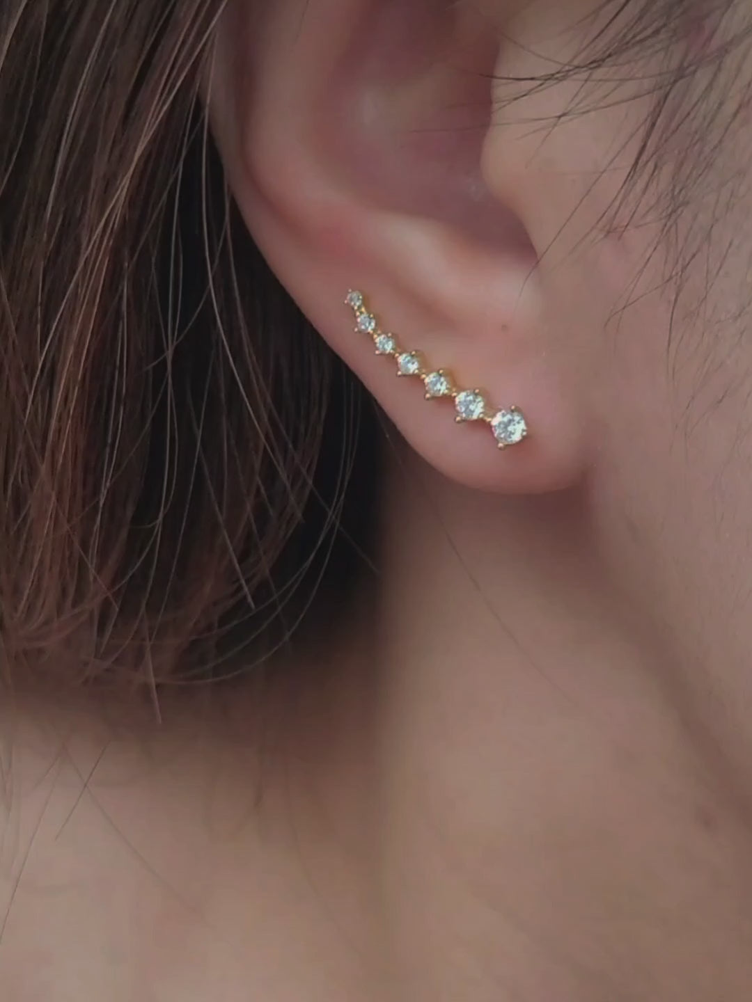 Close-up of a woman&#39;s ear wearing an 18K gold-plated cubic zirconia climber earring, highlighting the elegant and minimalist design.