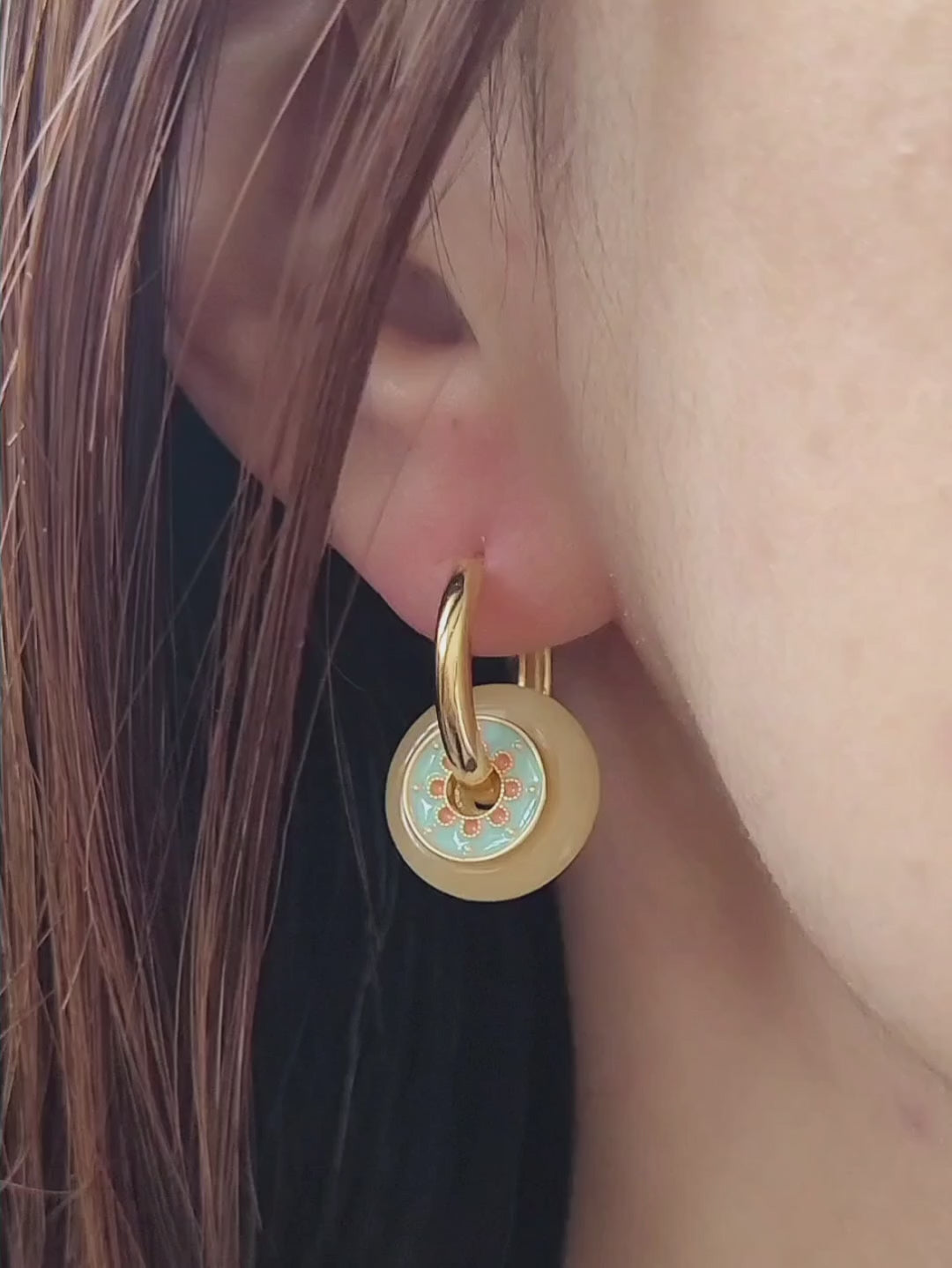 Close up of a woman wearing vintage-inspired enamel disc earrings with yellow glass drop and gold-plated hoops.